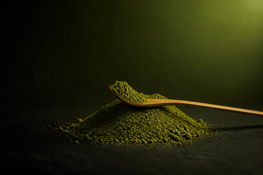A mound of fine matcha powder with a bamboo scoop resting on it